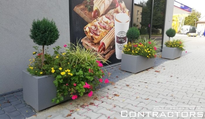 Donice betonowe z kwiatami przy stacji benzynowej